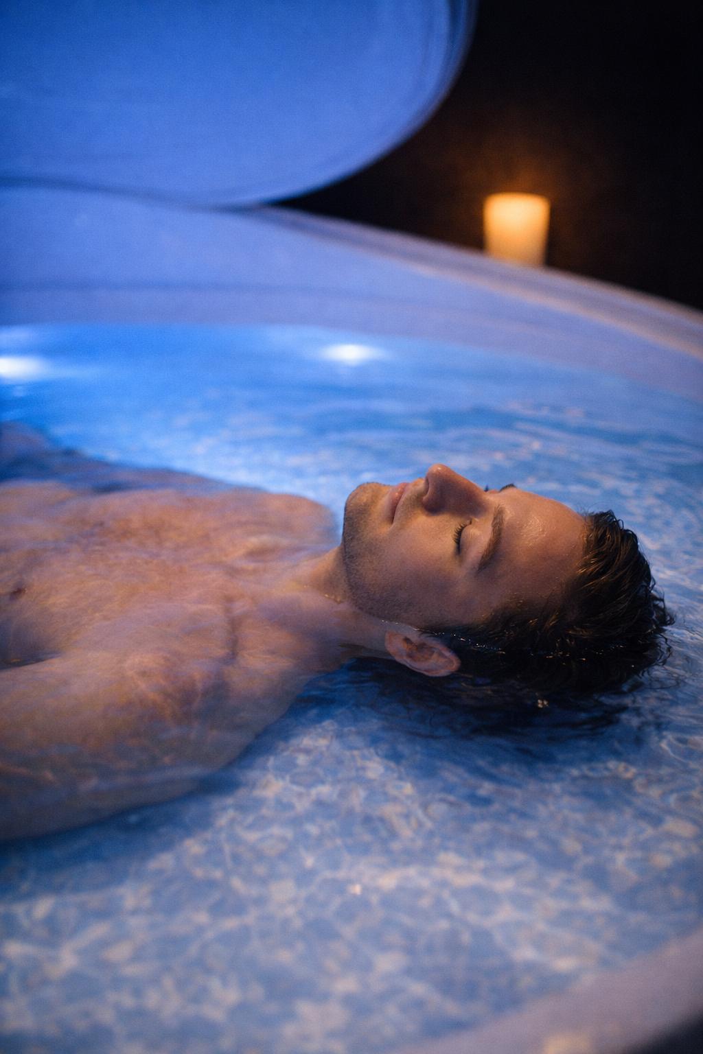 Homme en flottaison à la surface de l'eau, à la lueur d'une bougie — Serenity Sphere Metz